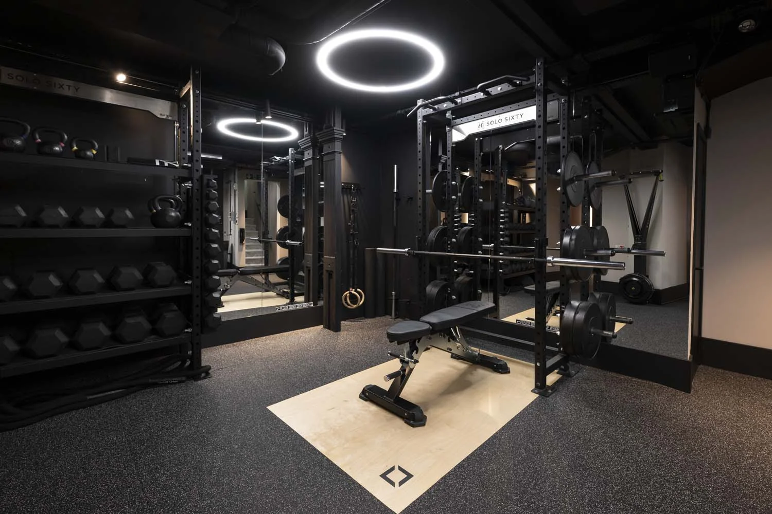 Private London training area with a squat rack, bench, dumbbells and kettlebells